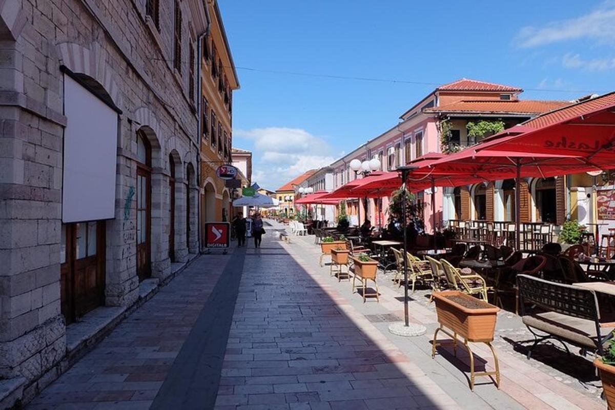 una strada con sedie, tavoli e ombrelloni rossi
