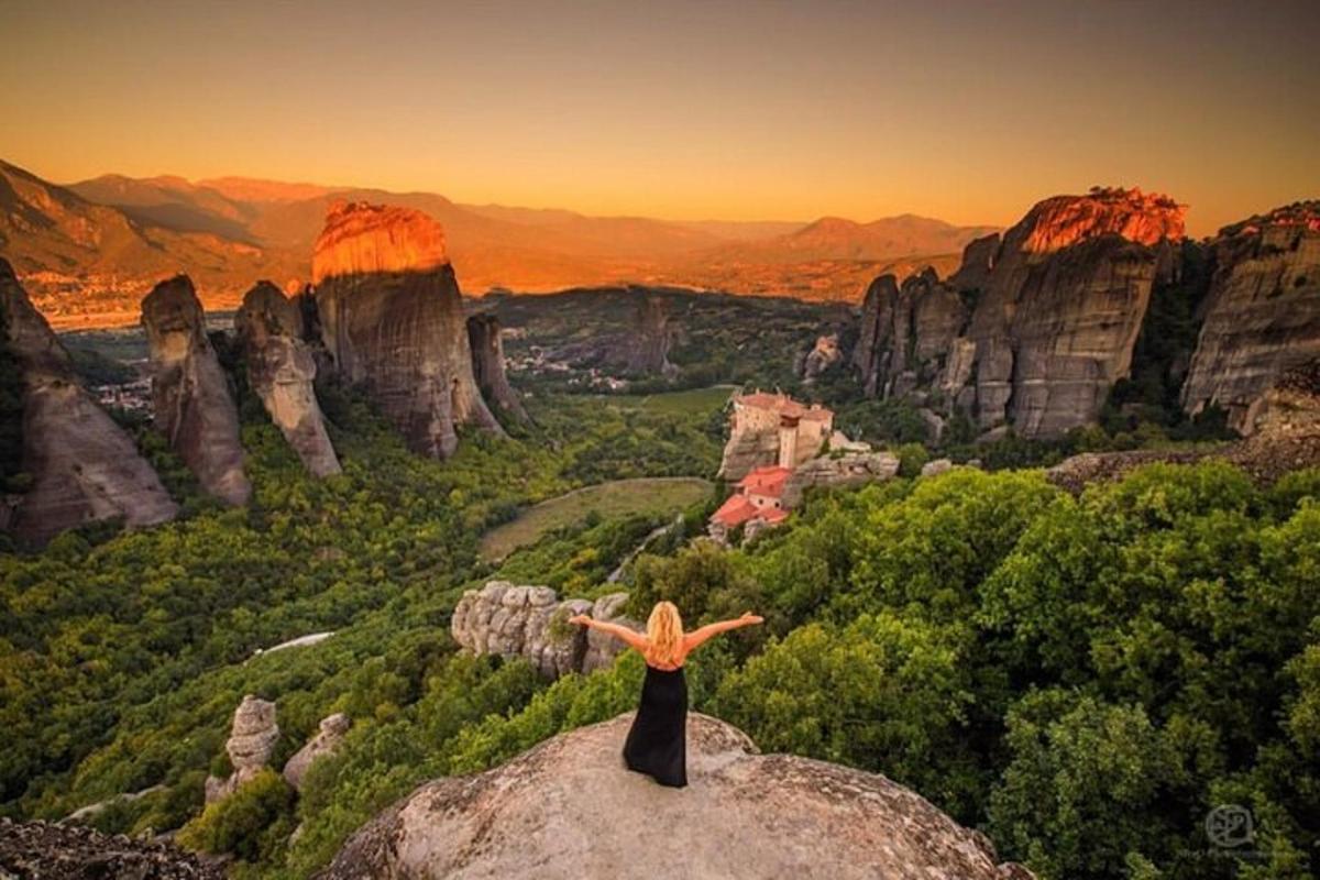 a woman standing on a rock with her arms outstretched