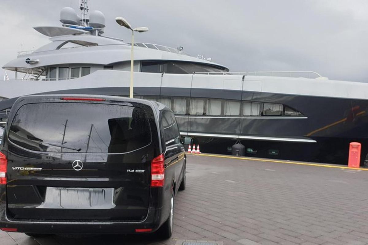 črn kombi parkiran poleg velikega čolna