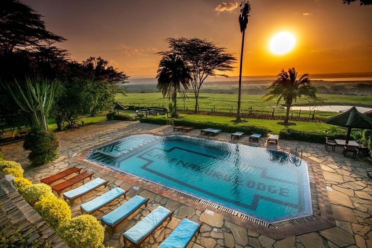 una piscina amb cadires i una posta de sol al fons