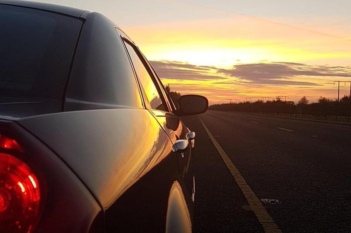un'auto parcheggiata sul ciglio di una strada con un tramonto