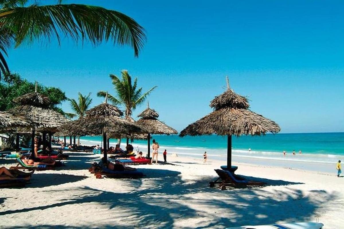 una spiaggia con ombrelloni di paglia e gente sulla spiaggia