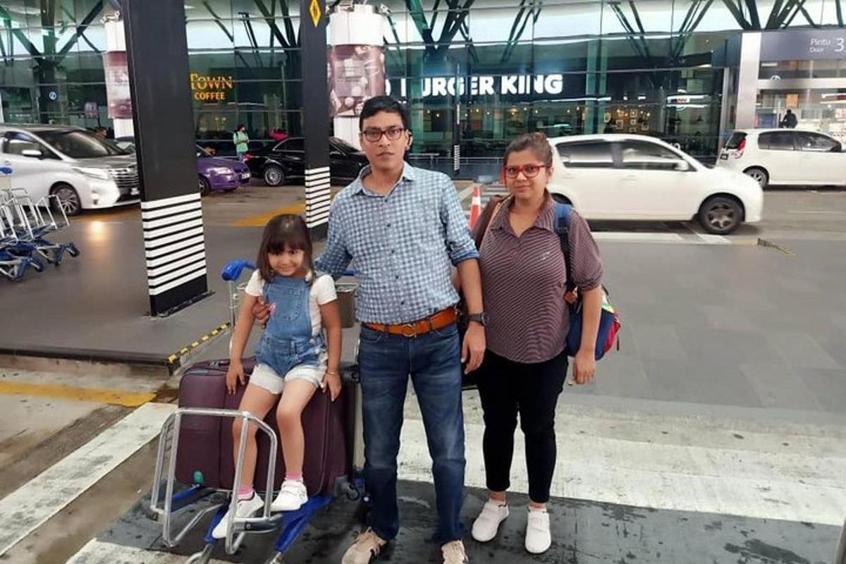 a man and woman with a little girl sitting on a luggage cart