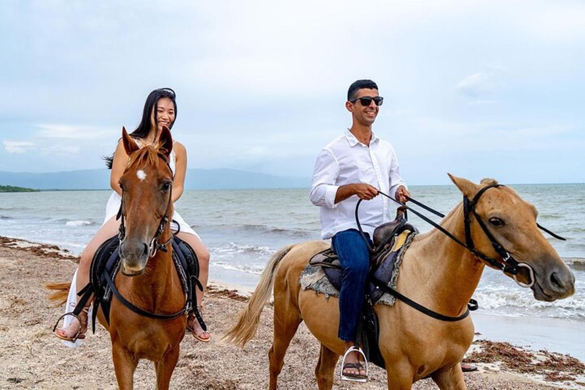 Un hombre y una mujer montando a caballo en la playa