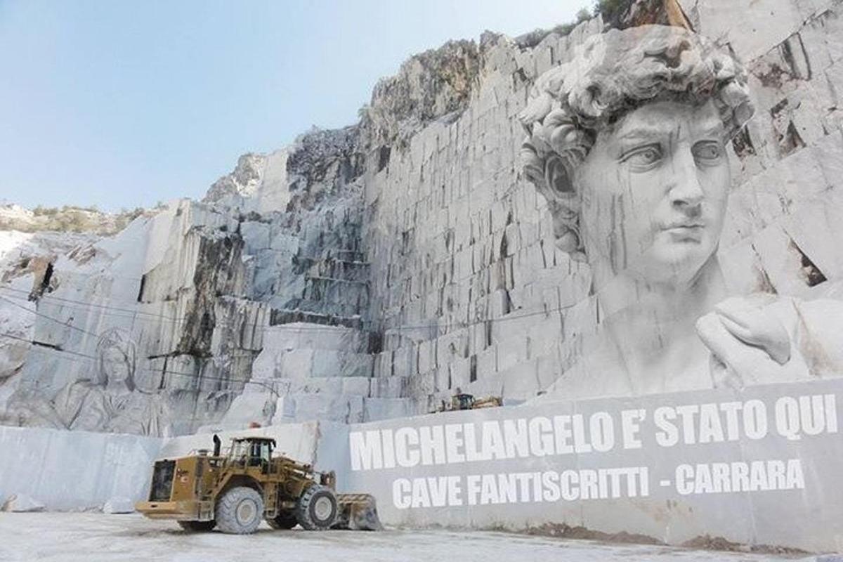 Un camión estacionado frente a un muro con una estatua.