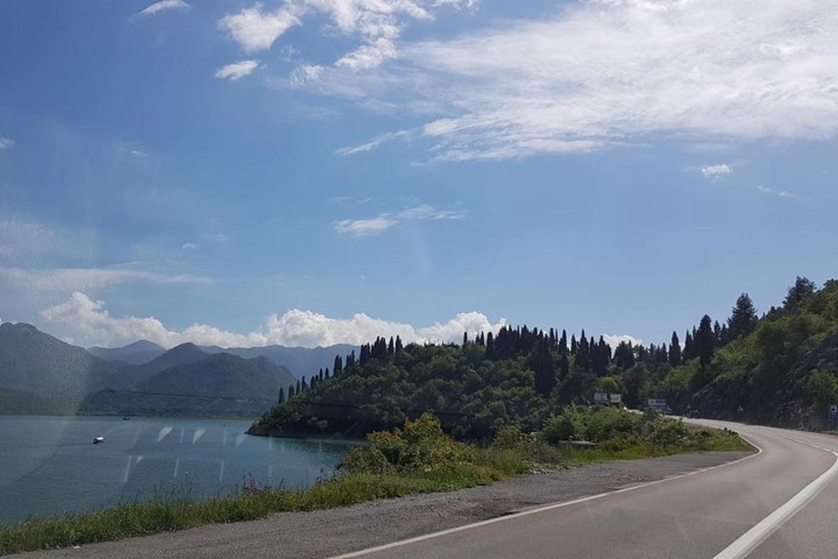 uma estrada com vista para um lago e montanhas