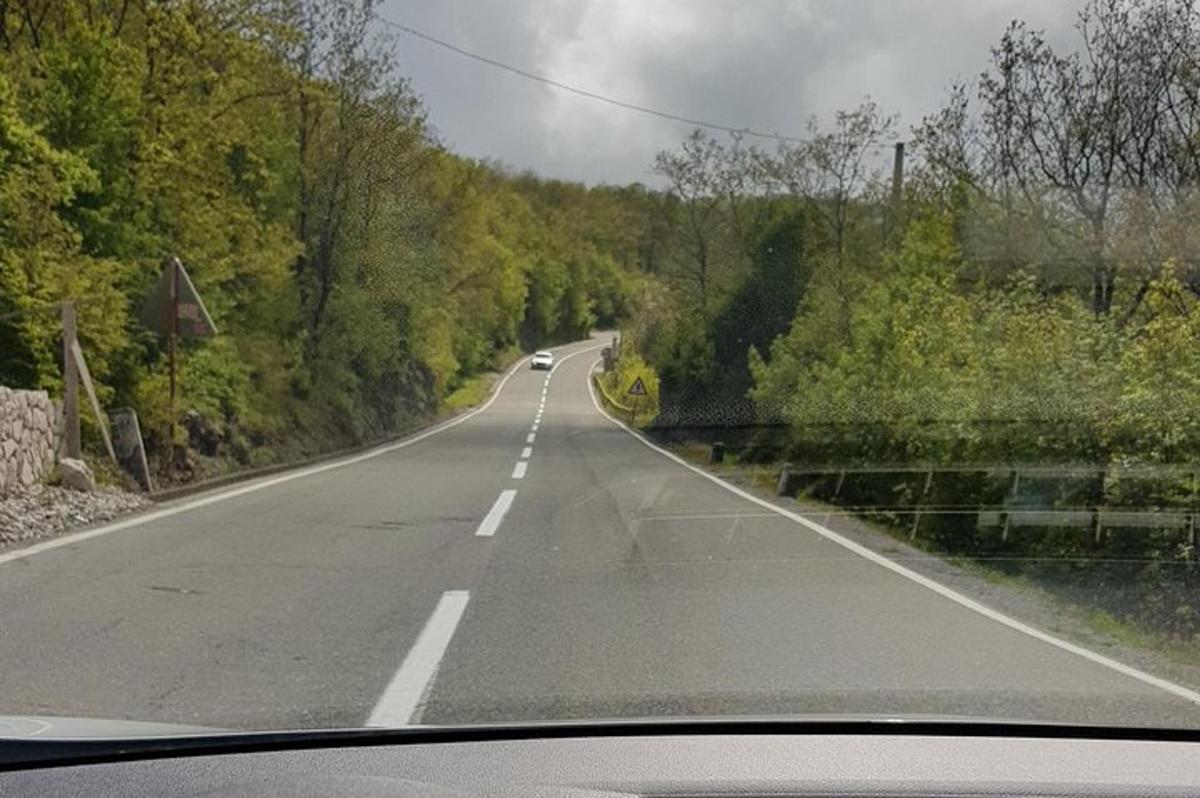 egy üres út, amelyen egy autó halad végig