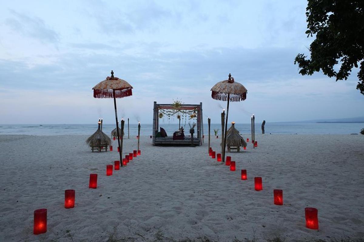 una cerimonia sulla spiaggia con candele rosse e ombrelloni