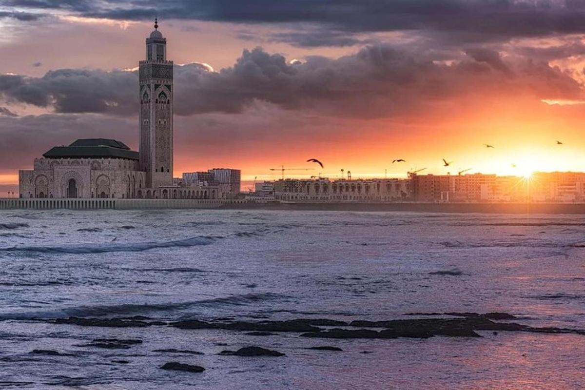 Un edificio con una torre de reloj en la playa al atardecer.