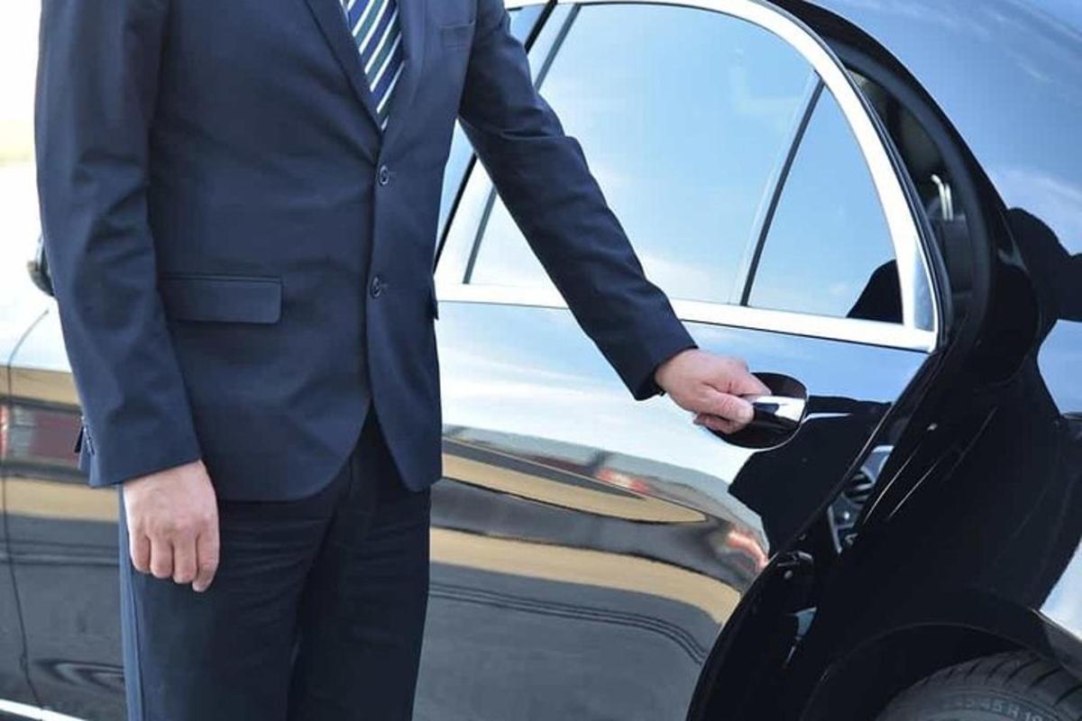 Un hombre con traje de pie junto a un coche.