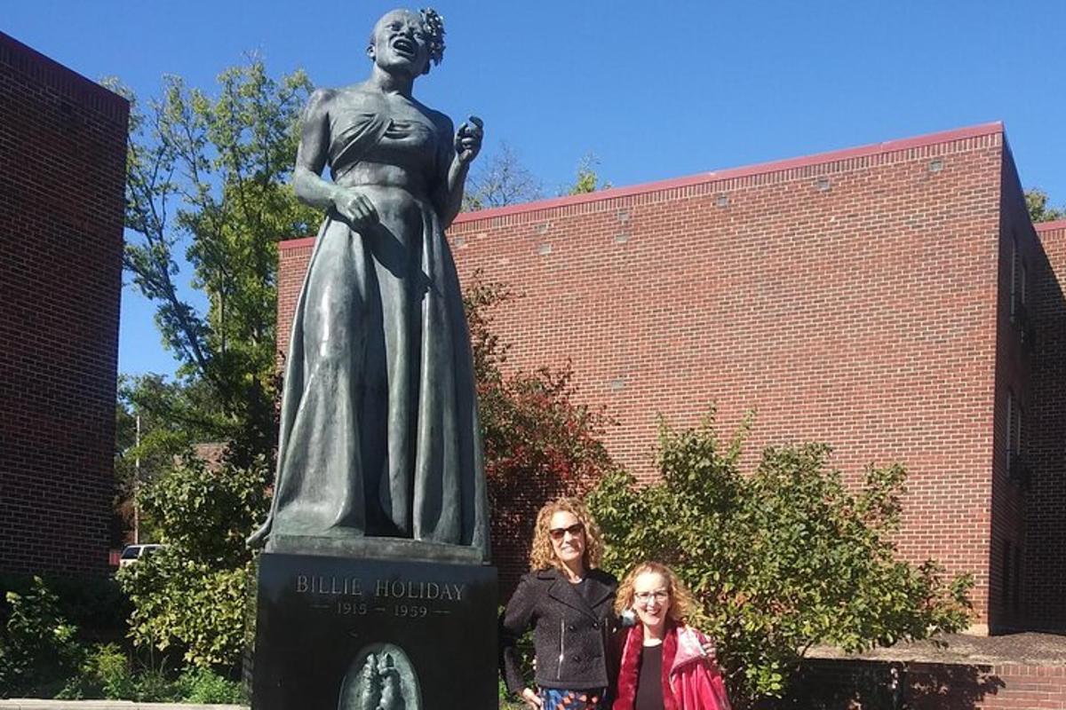 two women standing in front of a statue of a woman