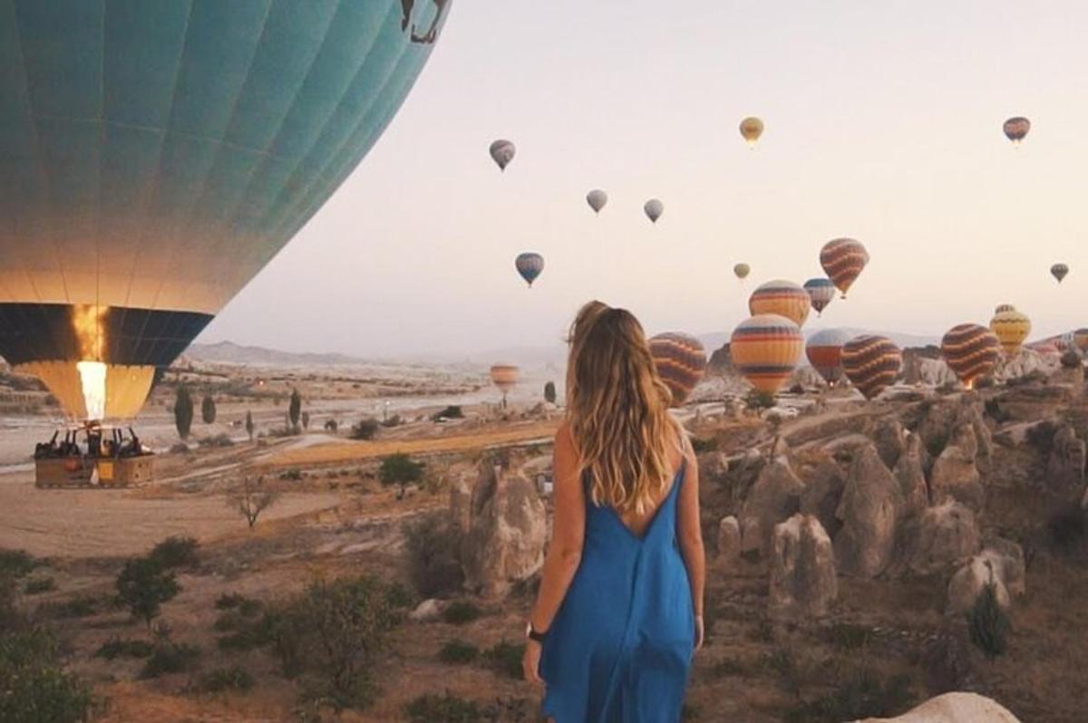 a woman in a blue dress looking at hot air balloons