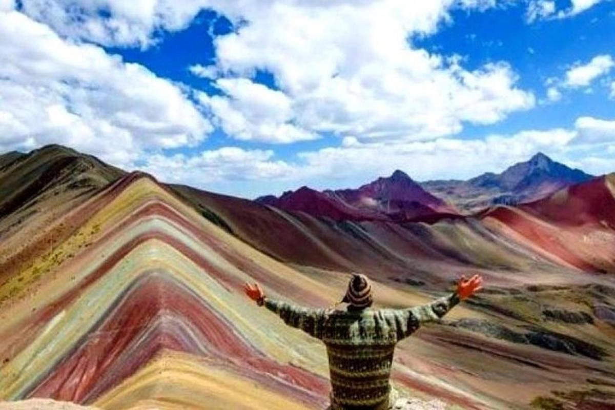 un uomo in piedi davanti a un dipinto di una montagna