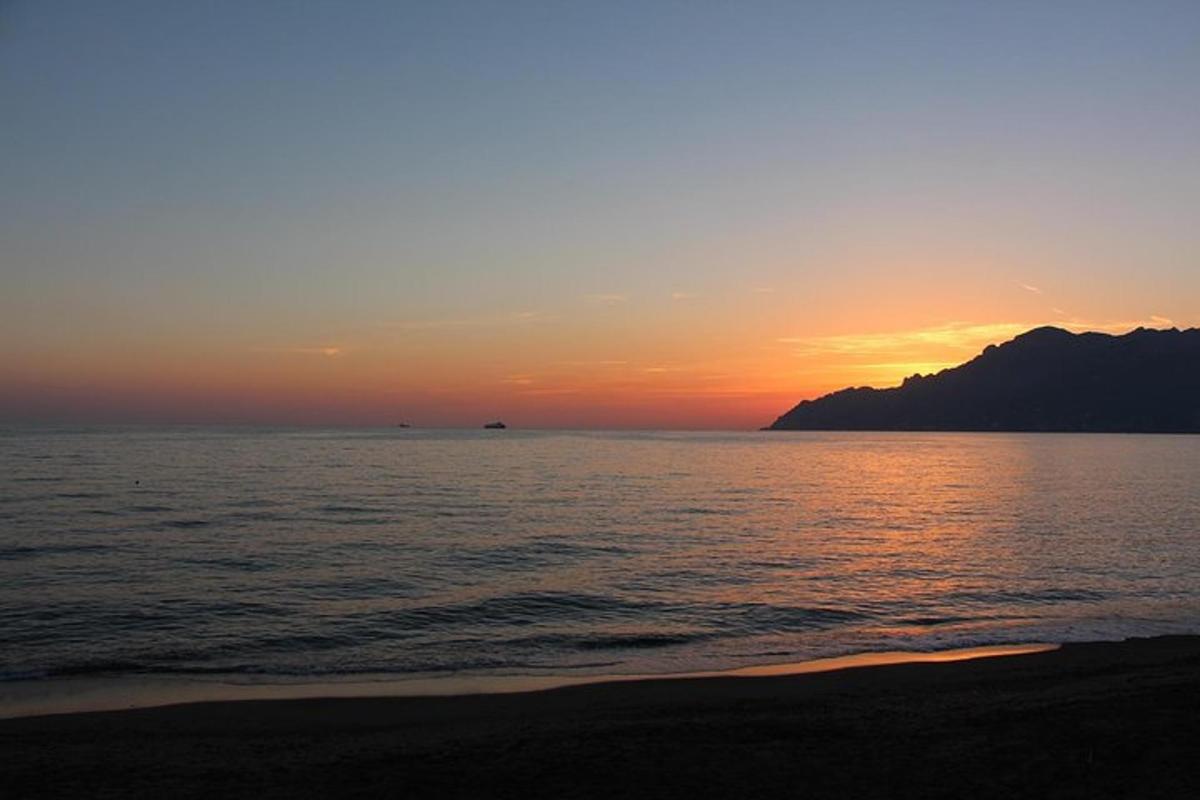 a sunset over the ocean with a mountain in the background