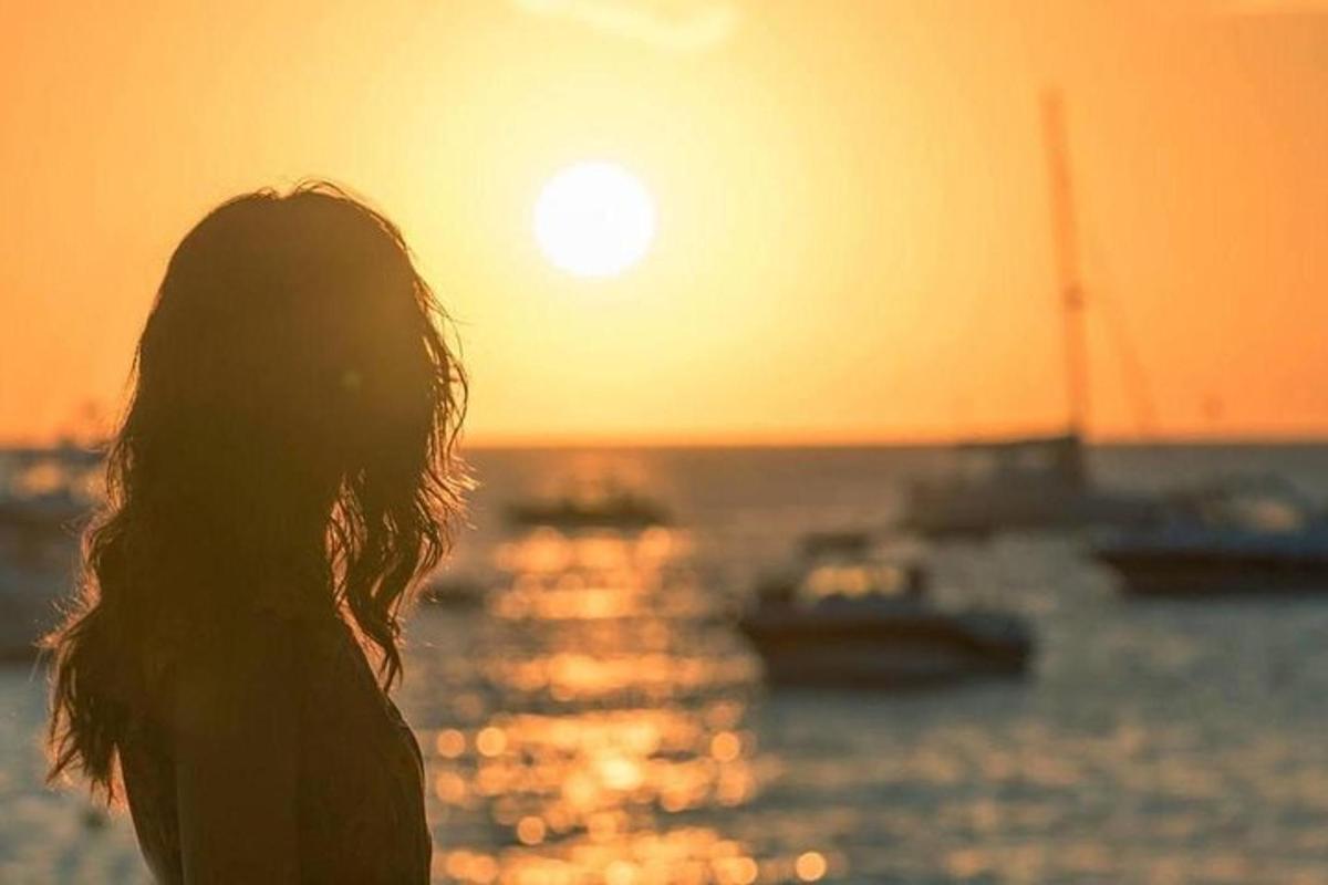 Μια γυναίκα που στέκεται μπροστά στον ωκεανό στο ηλιοβασίλεμα