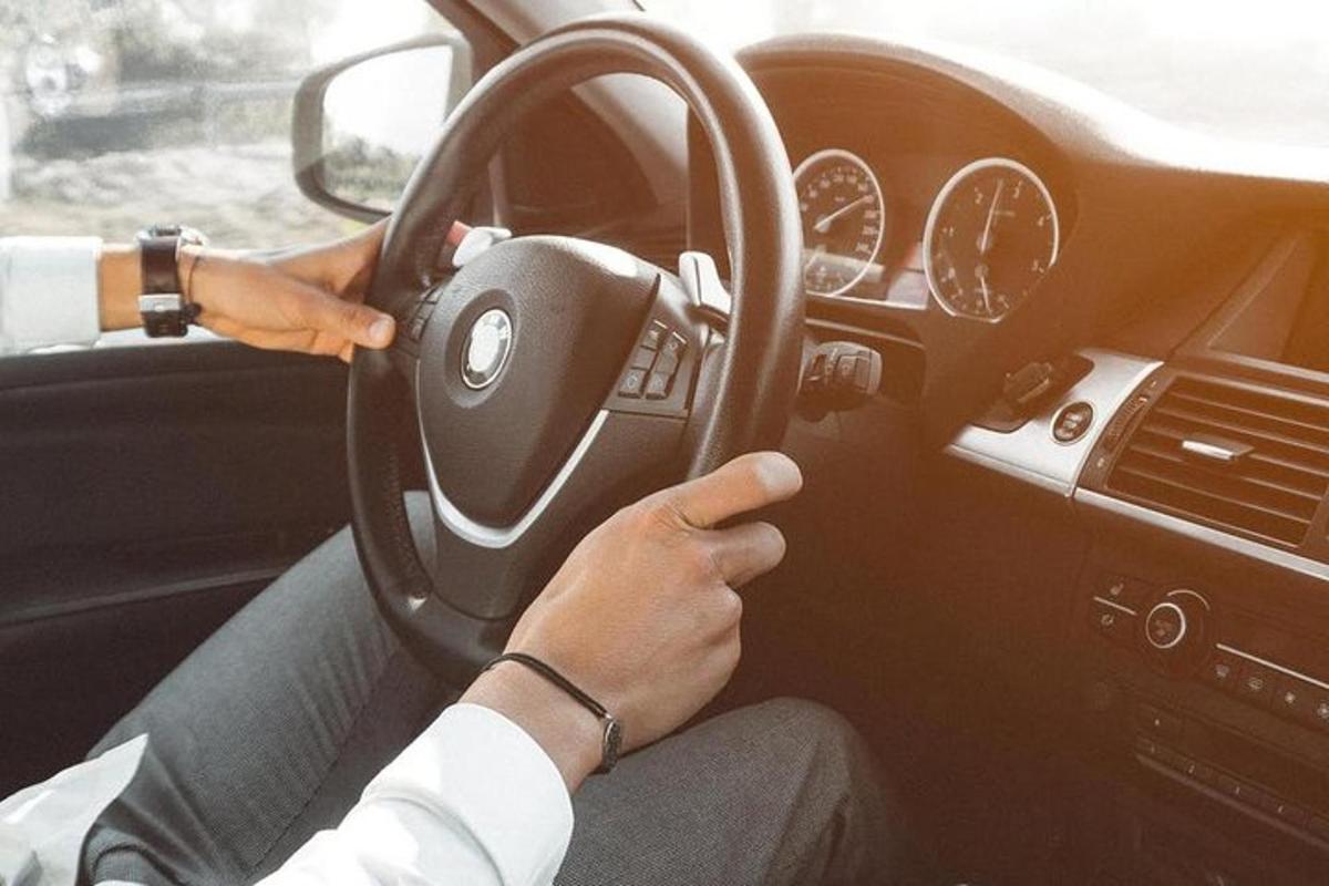 osoba řídící auto a zároveň držící volant