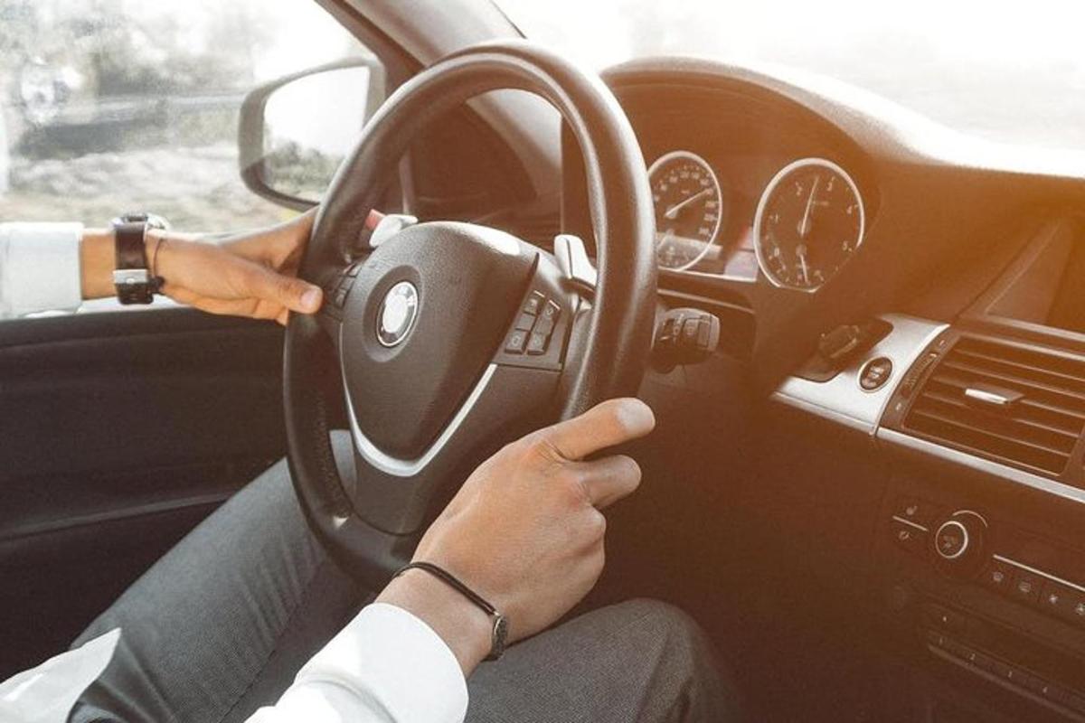 una persona che guida un'auto tenendo il volante