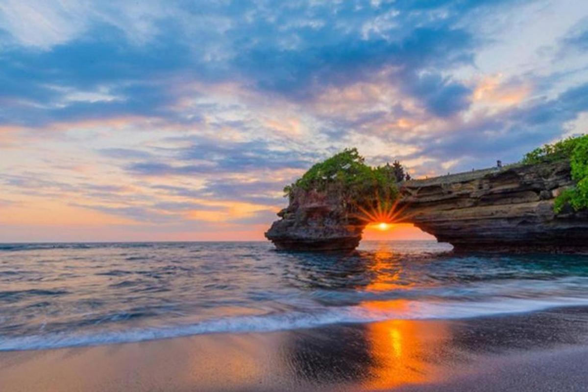 matahari terbenam di atas lautan berhampiran pembentukan batu besar