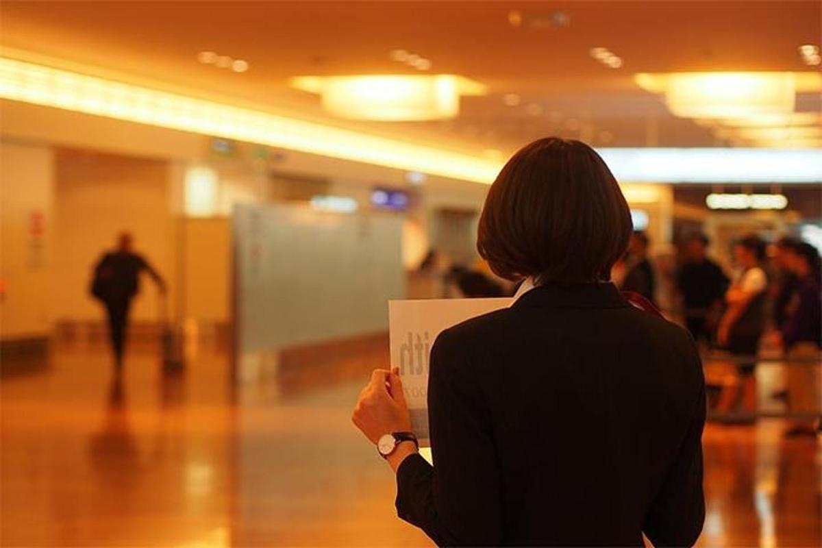 une femme debout dans un couloir tenant une pancarte