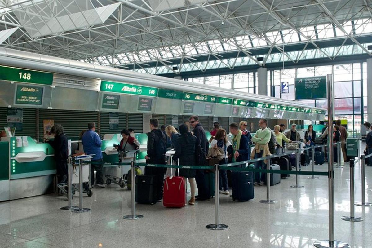 skupina lidí čekajících na svá zavazadla na letišti