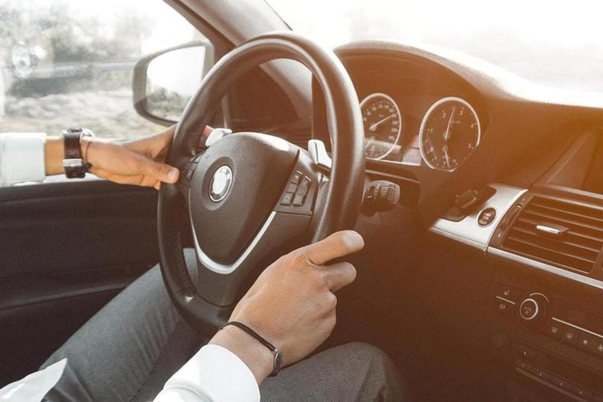 osoba šoférujúca auto a zároveň držiaca volant