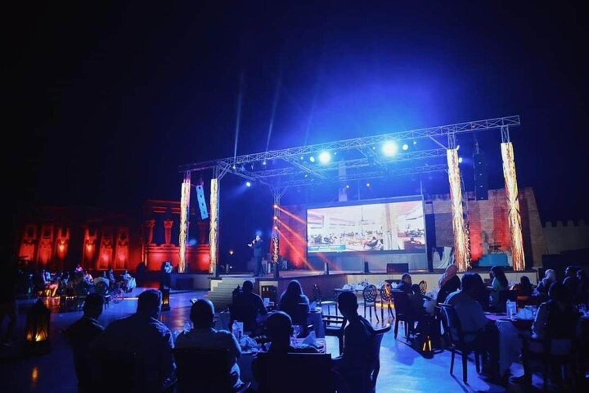 un gruppo di persone sedute ai tavoli davanti a un palco