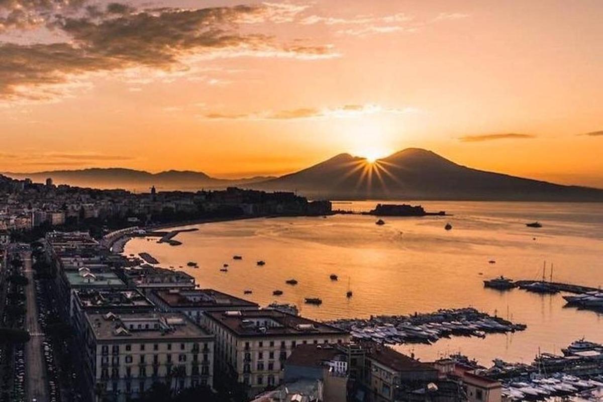 a sunset over a city with a harbor with boats