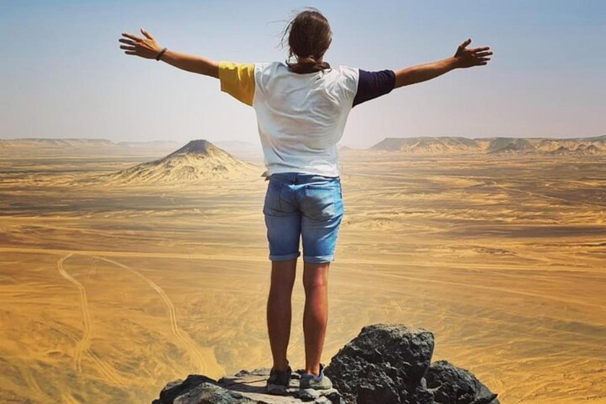 a woman standing on a rock with her arms outstretched