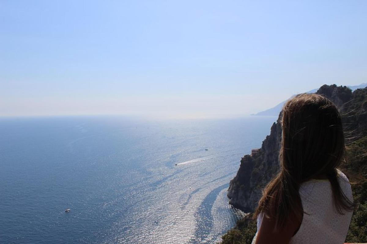 una donna in piedi su una scogliera che guarda l'oceano