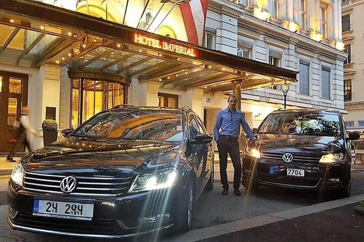 a man standing next to two cars in front of a building