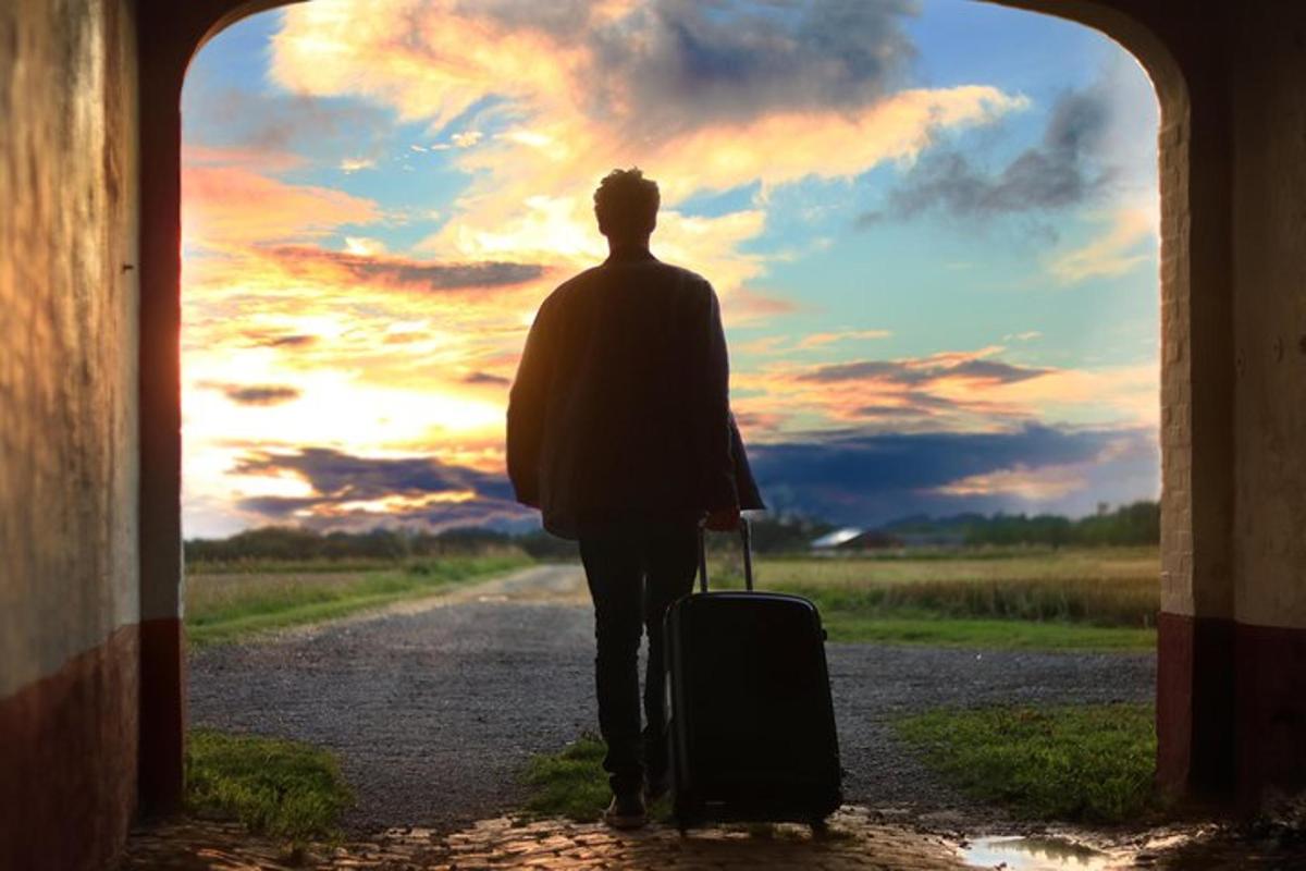 um homem caminhando pela estrada com uma mala