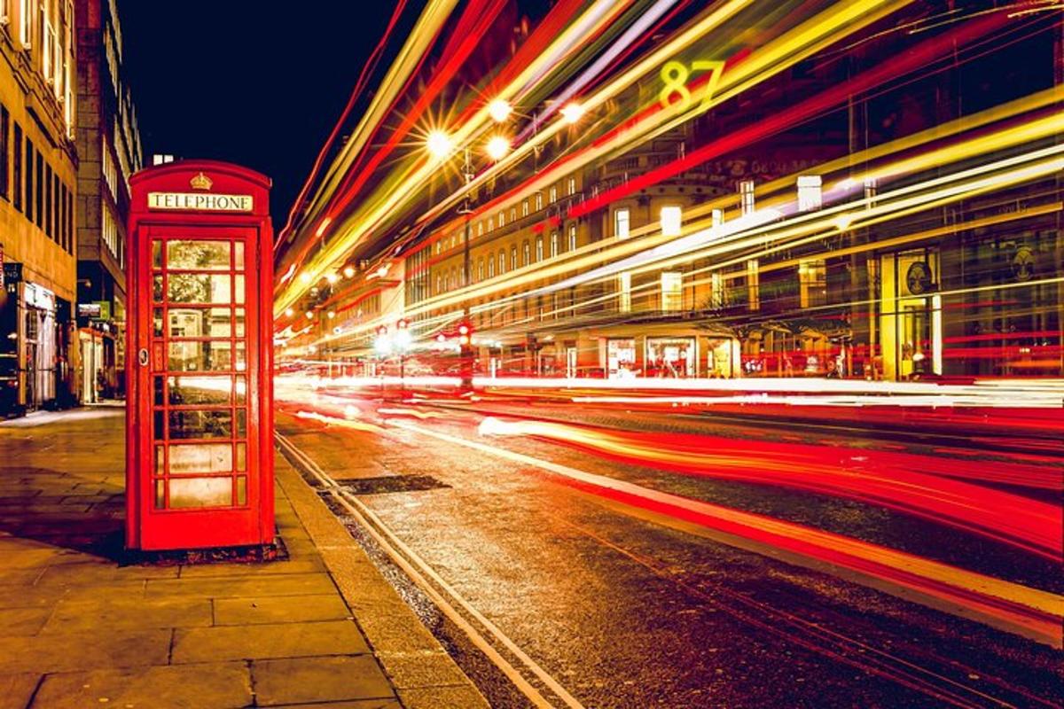 uma cabine telefônica vermelha em uma rua da cidade à noite