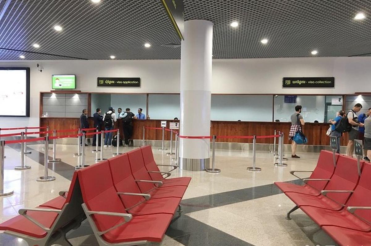 um grupo de pessoas em pé em um aeroporto com cadeiras vermelhas