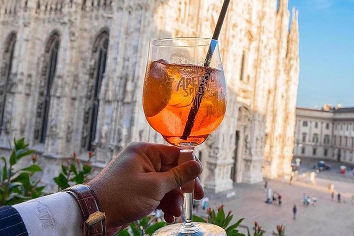 una persona che tiene in mano un bicchiere di vino davanti a un edificio