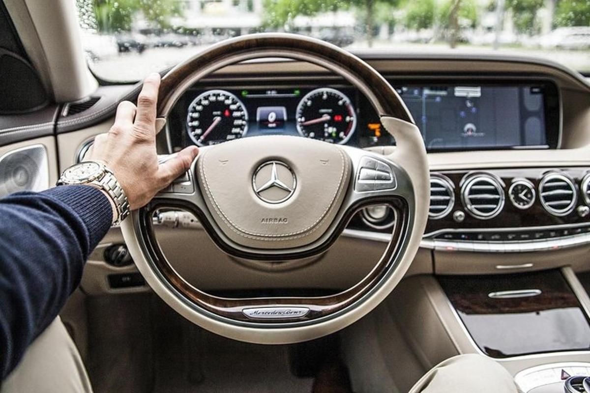 seorang lelaki memandu kereta mercedes benz dengan tangannya di atas stereng