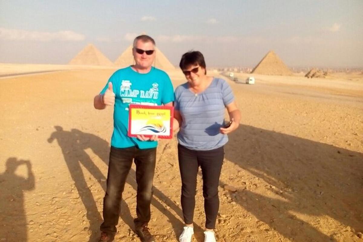 muž a žena držící pamětní desku před pyramidami