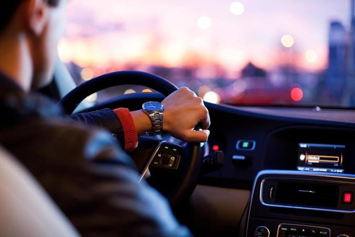 a person driving a car with their hand on the steering wheel