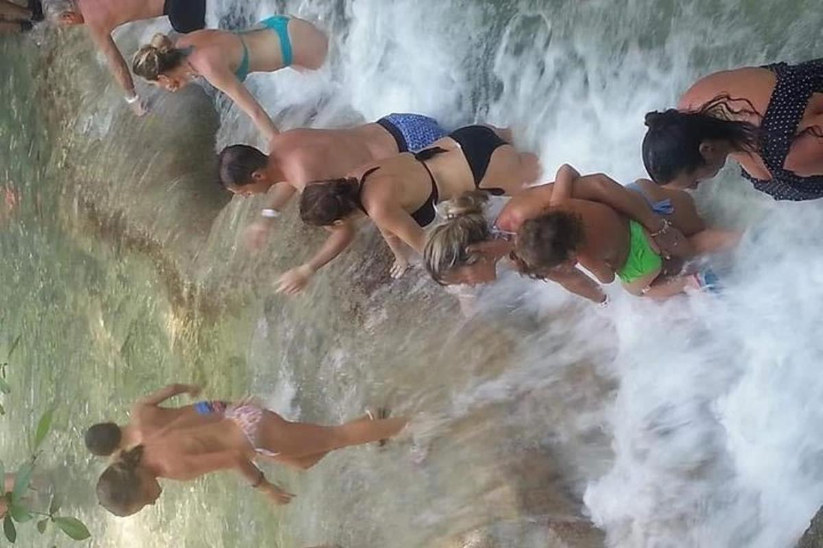група људи стоји у води близу водопада