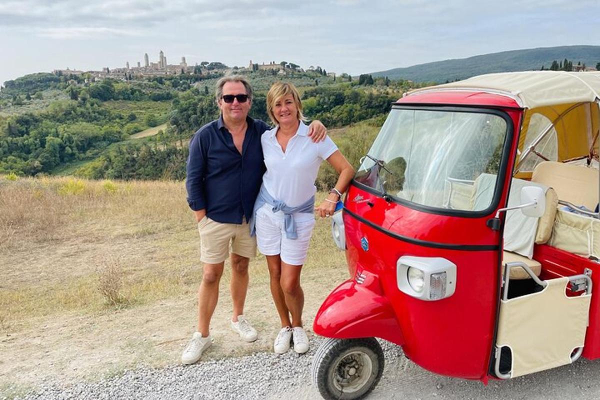 um homem e uma mulher em pé ao lado de um carrinho de golfe vermelho