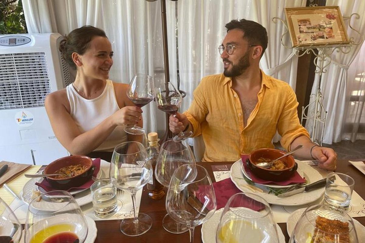 um homem e uma mulher sentados à mesa com taças de vinho