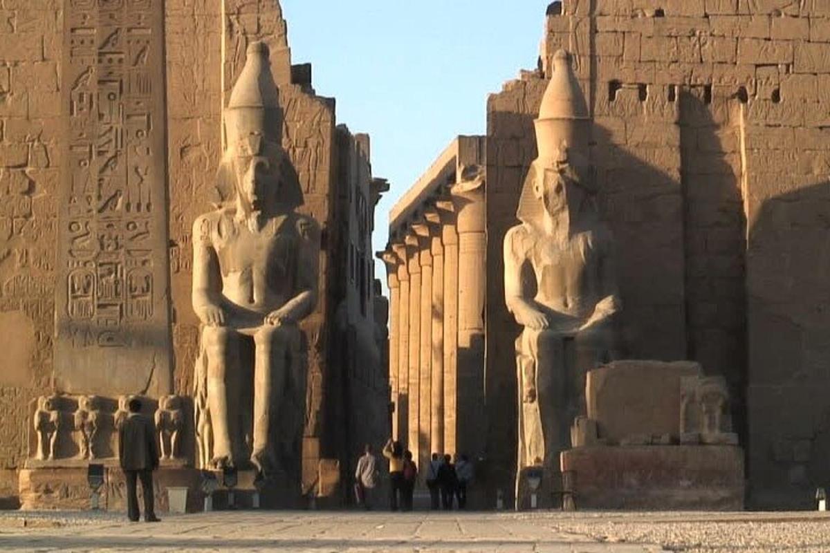 Un grupo de personas de pie junto a dos grandes estatuas.