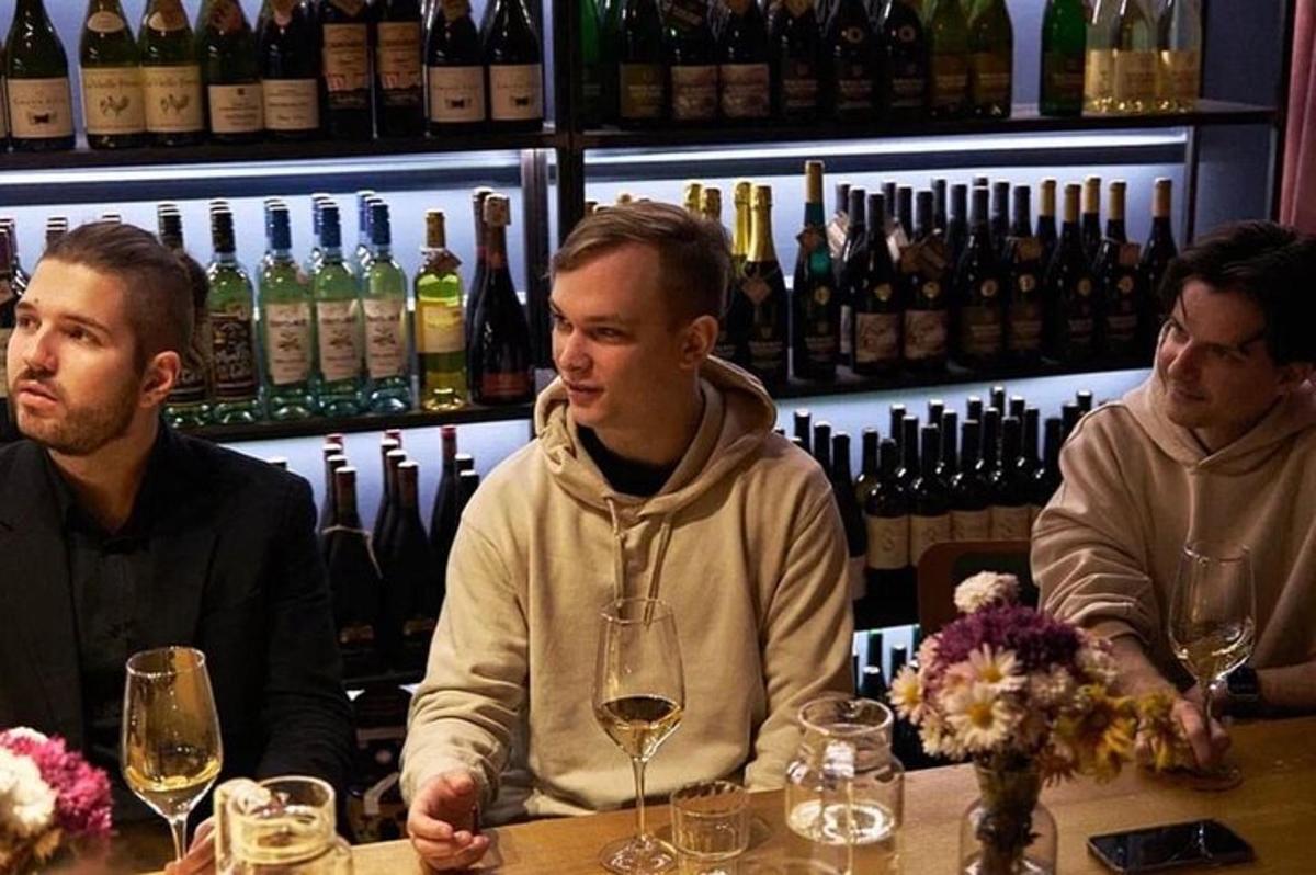 trzech mężczyzn siedzących przy barze z kieliszkami do wina