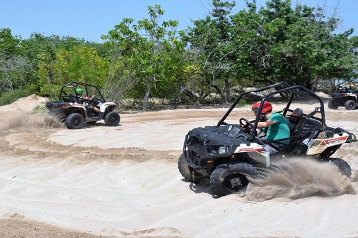 duas pessoas andando de quadriciclo em uma estrada de terra