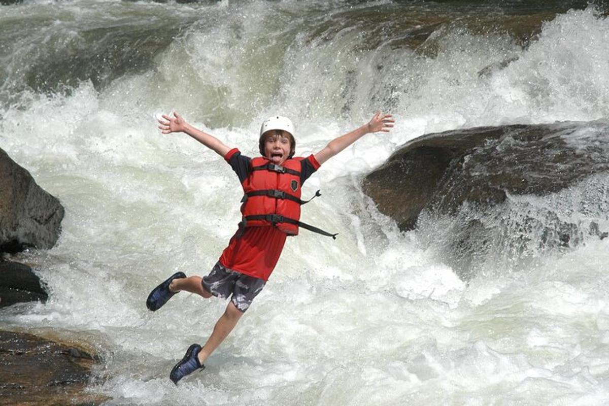 a young boy is jumping in a waterfall