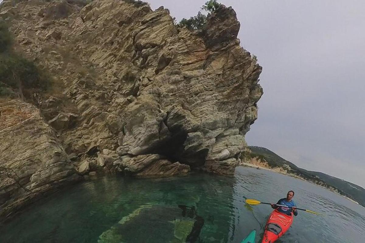 un uomo in kayak nell'acqua accanto a una montagna