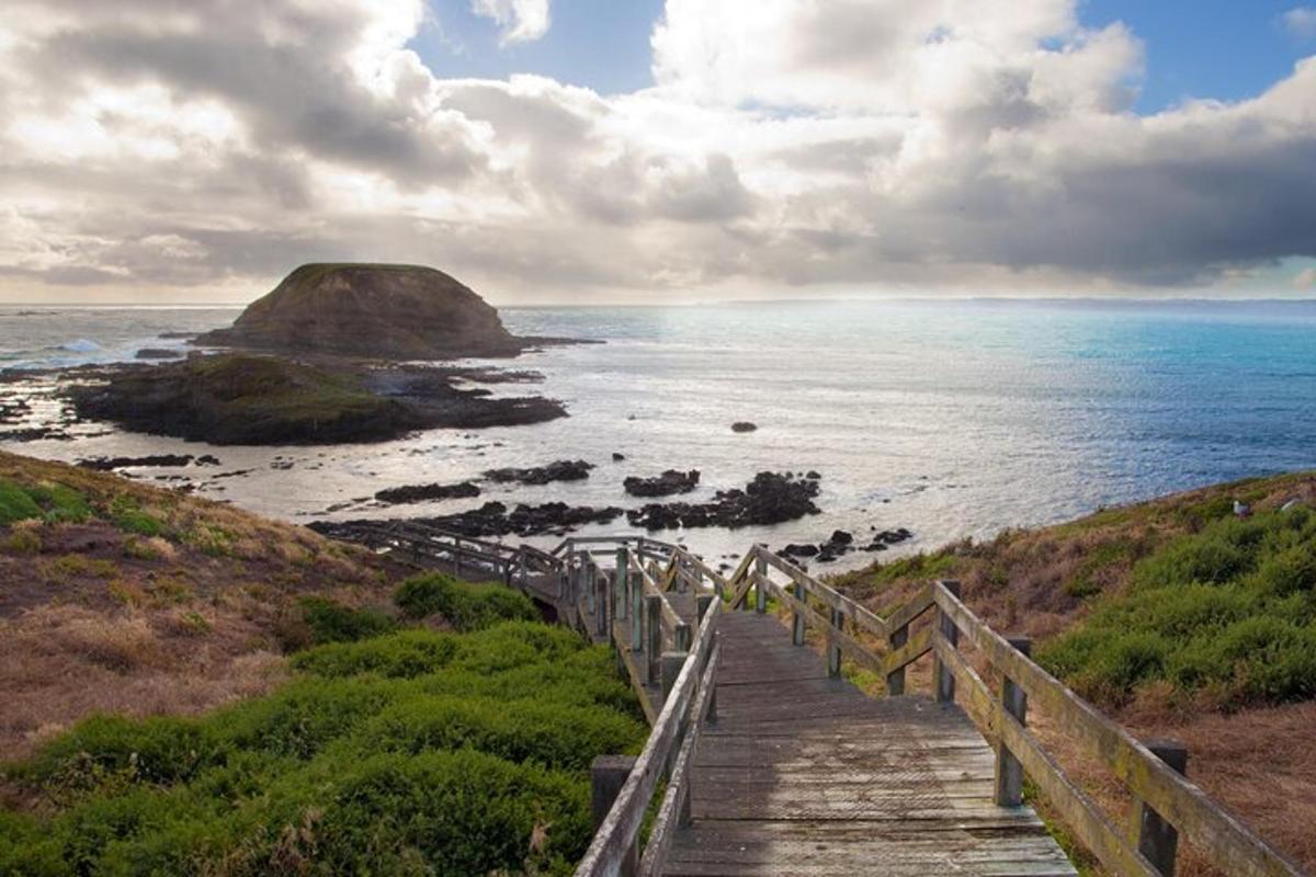 a wooden staircase leading to the ocean with a rock formation