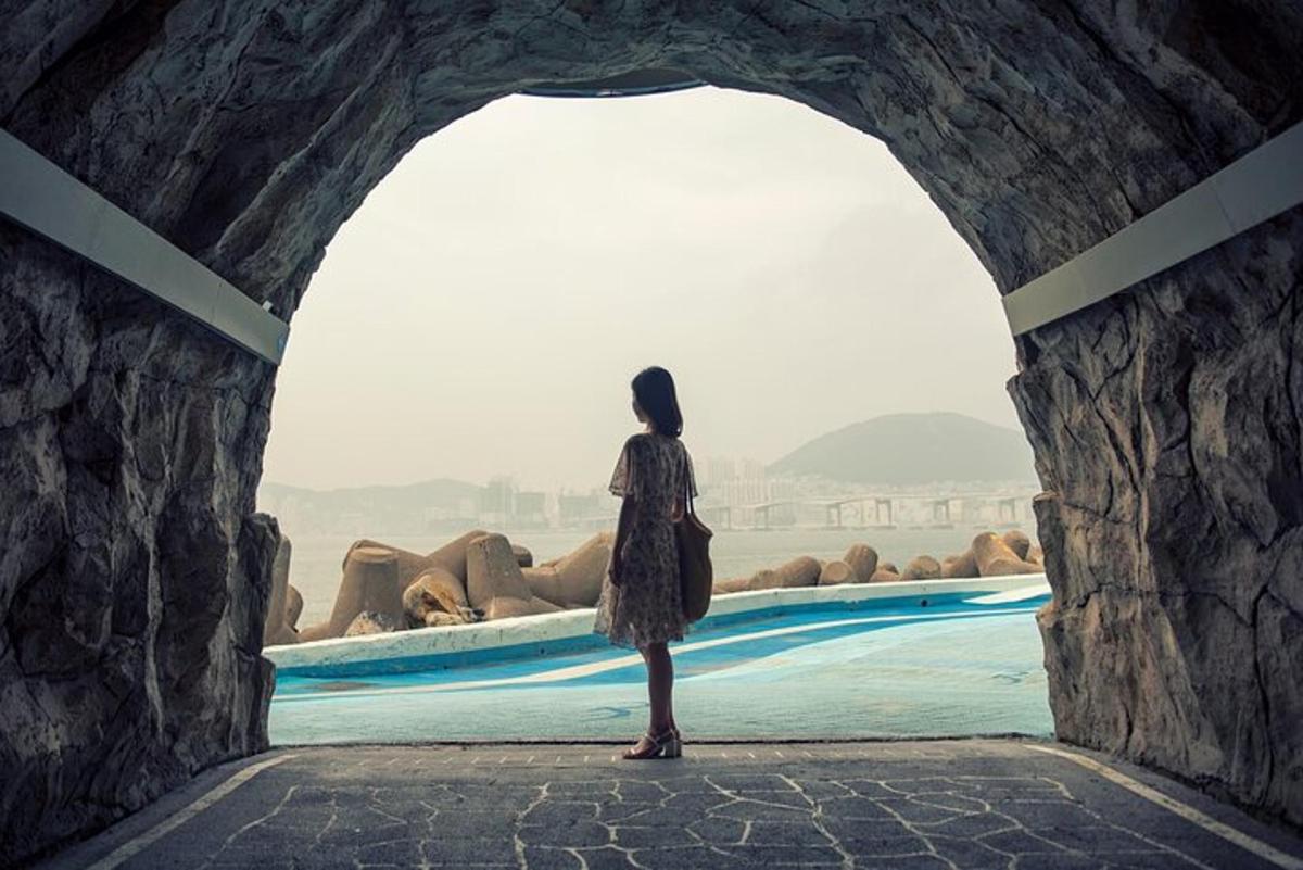 a woman standing in a tunnel looking at a pool