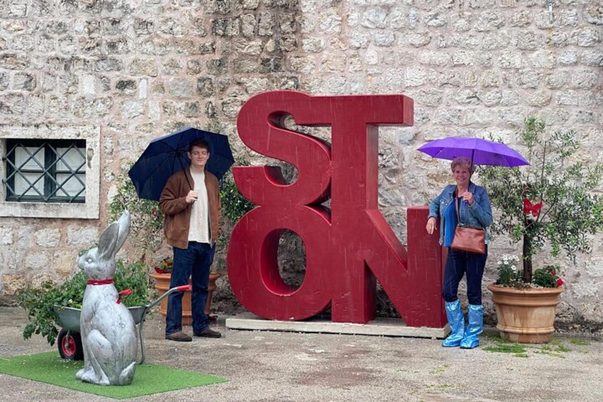 dva lidé s deštníky stojící vedle cedule s nápisem sr art