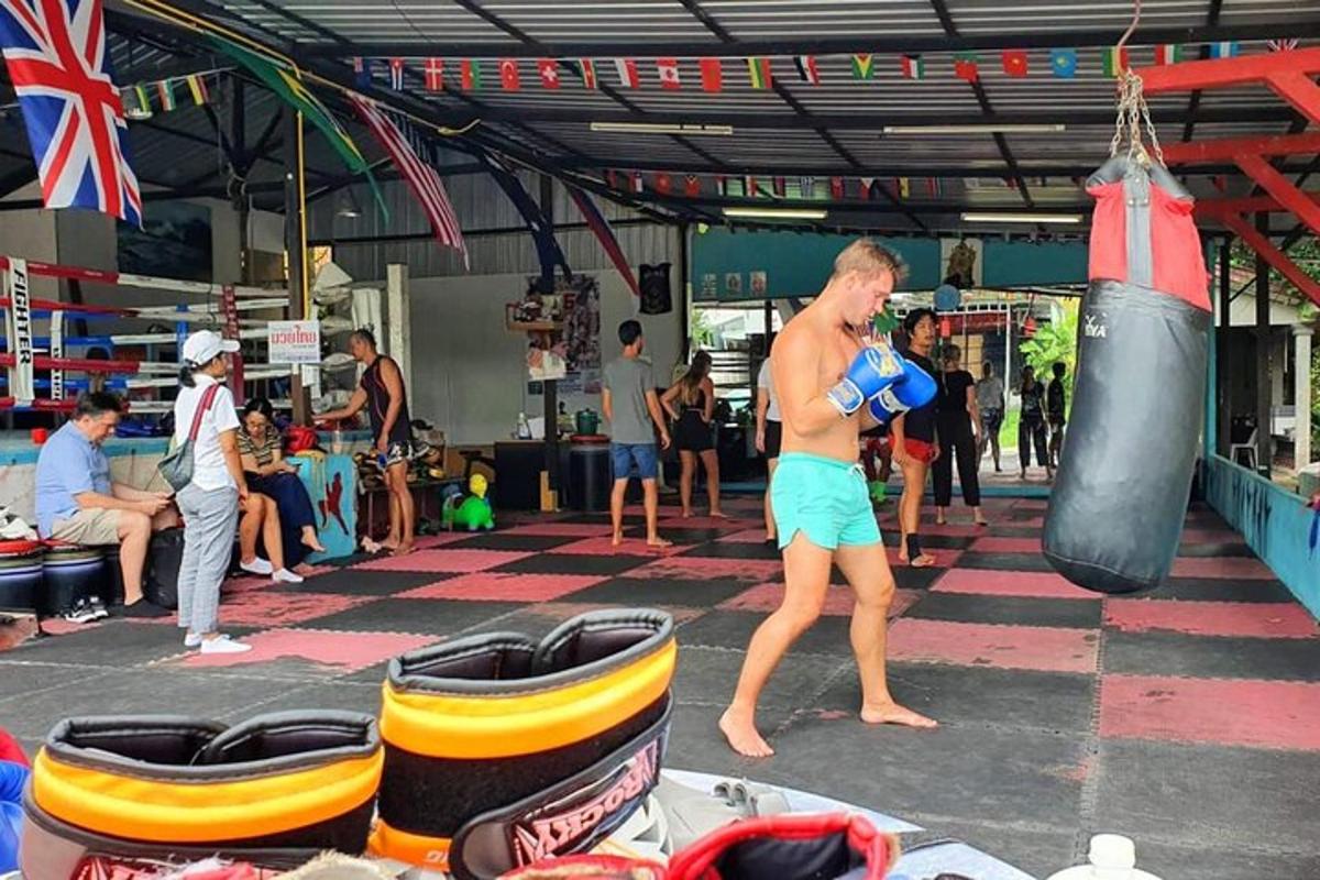 muž stojaci v telocvični s boxovacím vrecom
