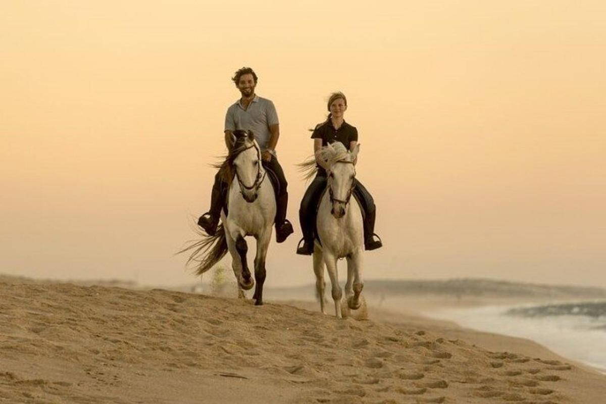 a man and a woman riding horses on the beach